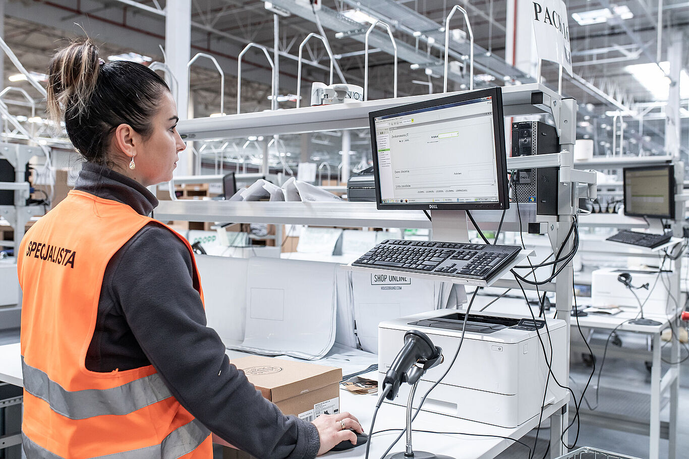 [Translate to Polski:] ine weibliche Lagerarbeiterin arbeitet mit PSIwms-Software am Computer zur Bestandsverwaltung.